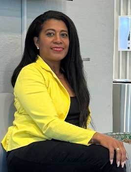 Portrait of Sayne, a leader of the organization, wearing a yellow blazer