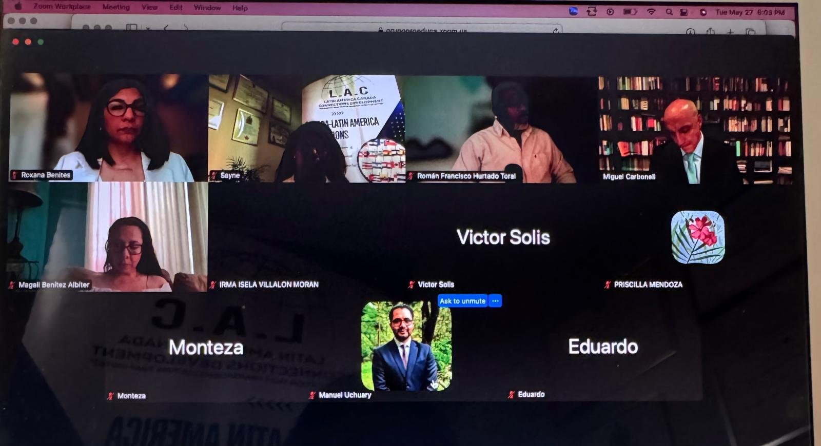 A laptop screen showing a video conference with multiple diverse participants engaged in a virtual academic meeting.